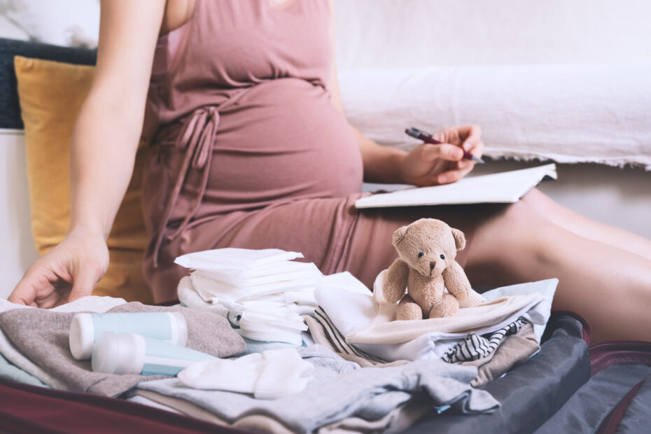 Schwangere Frau packt Tasche für Entbindungsklinik und macht Checkliste