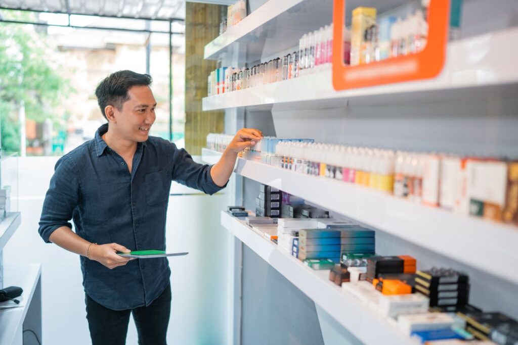 Mann im Vape Shop vor Regal mit Elfbar Liquids bei der Auswahl verschiedener Sorten