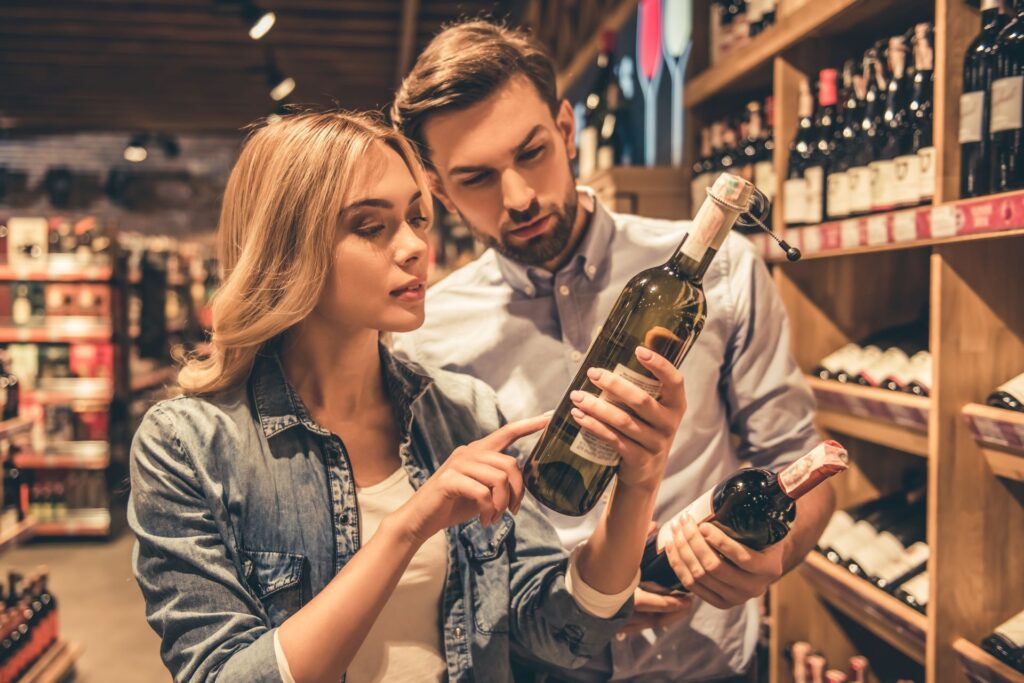 Frau und Mann prüfen Flaschenetikett beim Wein kaufen