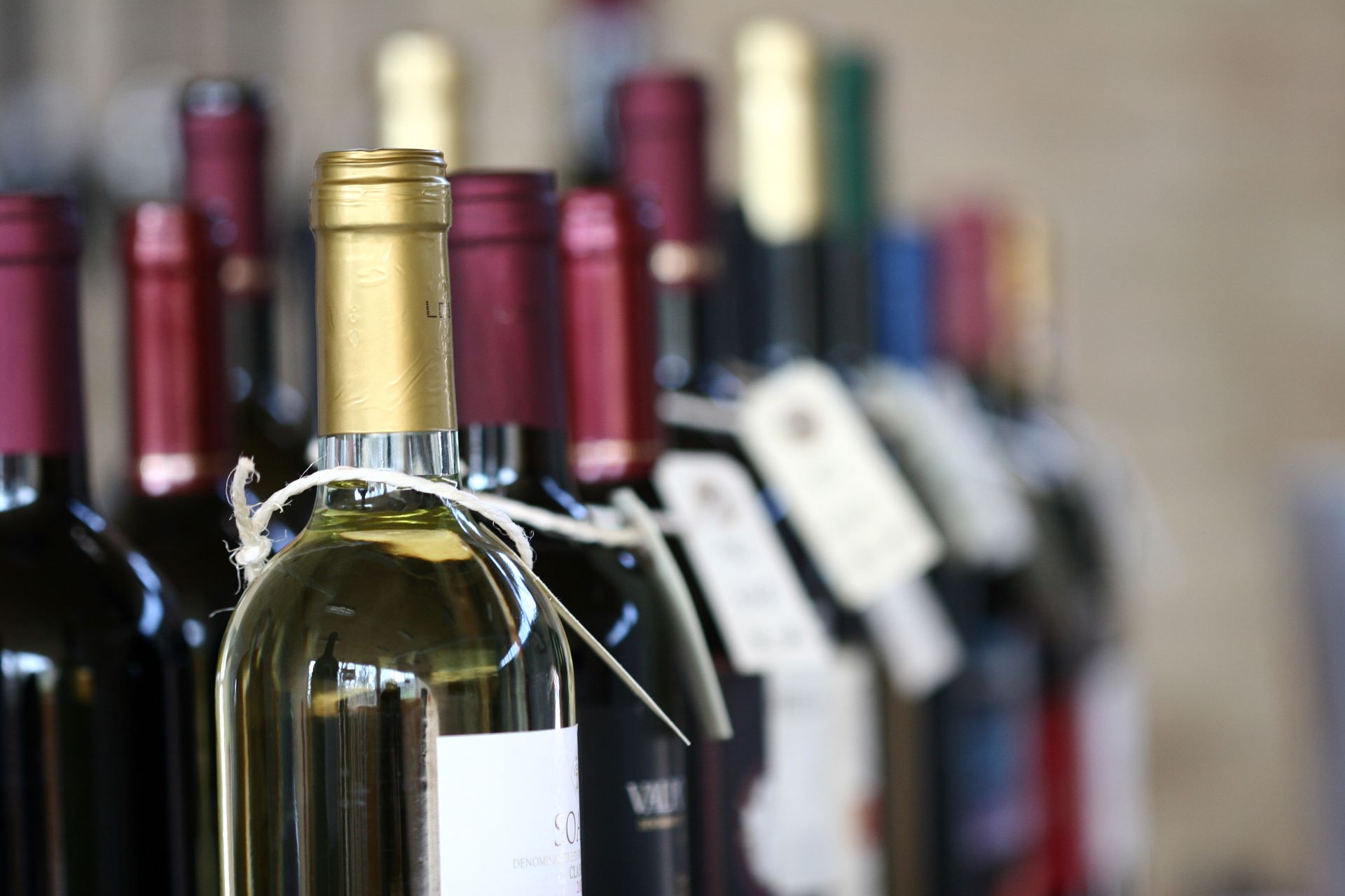 Weinflaschen mit Etiketten im Regal beim Wein kaufen